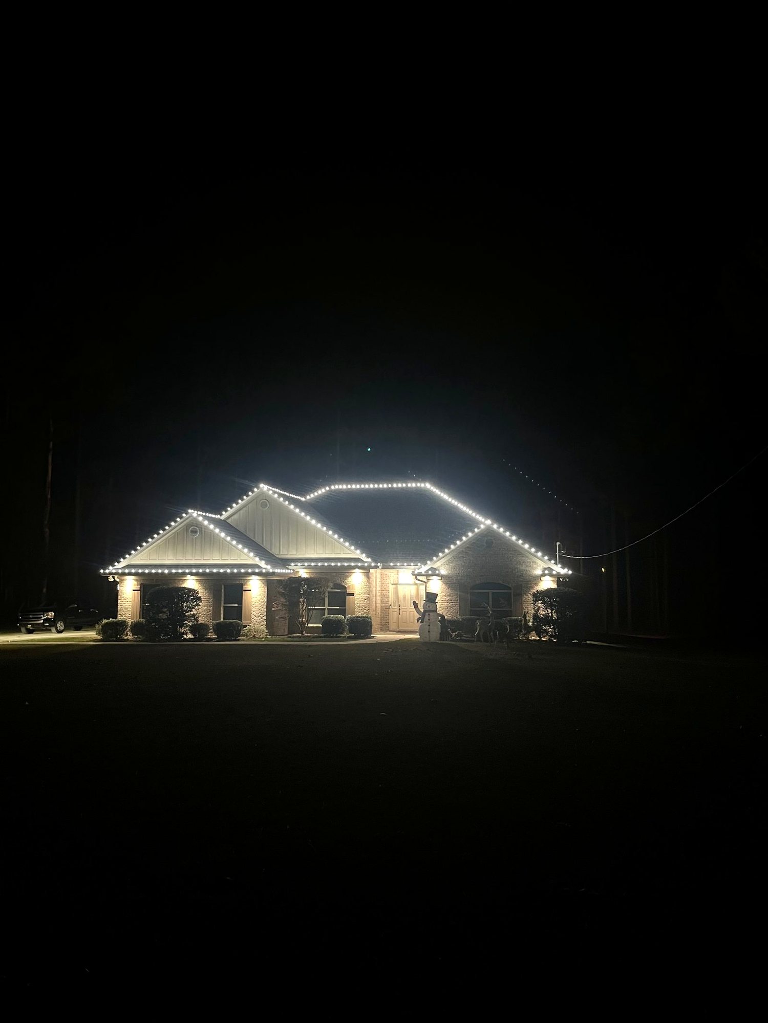 Two-story brick home outlined in C9 warm white bulbs at night