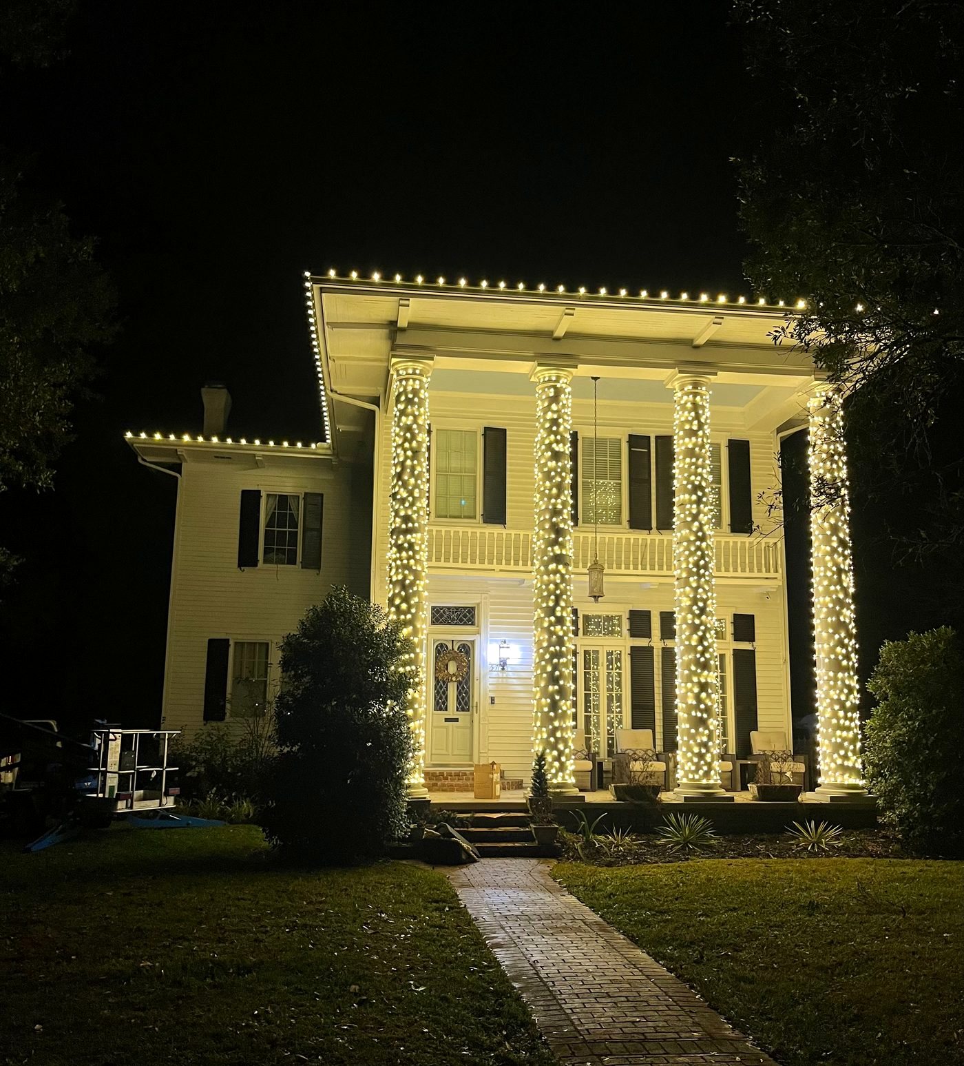 Historic home with columns fully wrapped in warm white lights