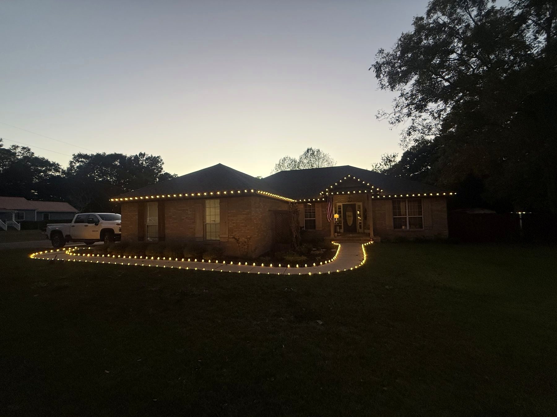 Brick ranch home with roofline and pathway lighting at dusk