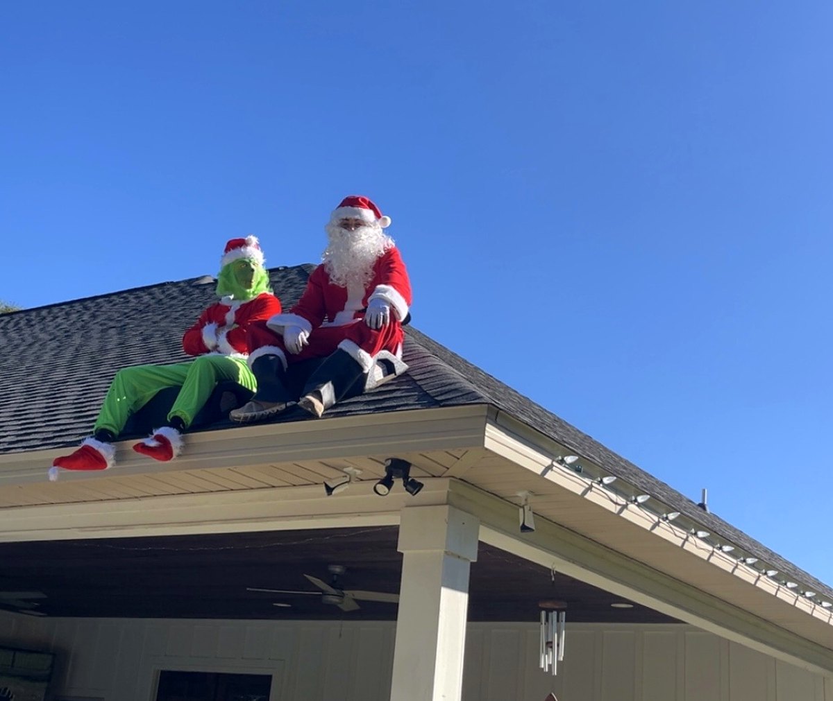 Top Notch Exterior Lighting crew in Santa and Grinch costumes on a customer's roof